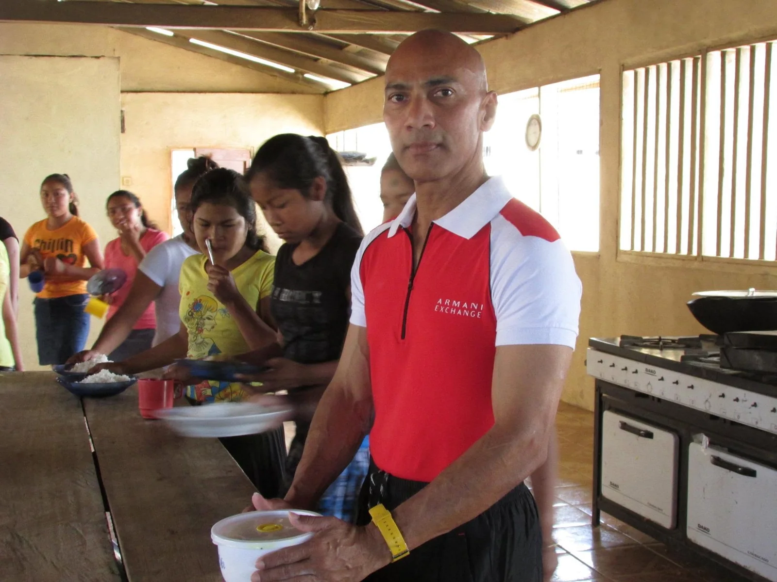 Roy Ramkissoon with students in a dorm kitchen during a volunteer teaching adventure in a remote community in Guyana.